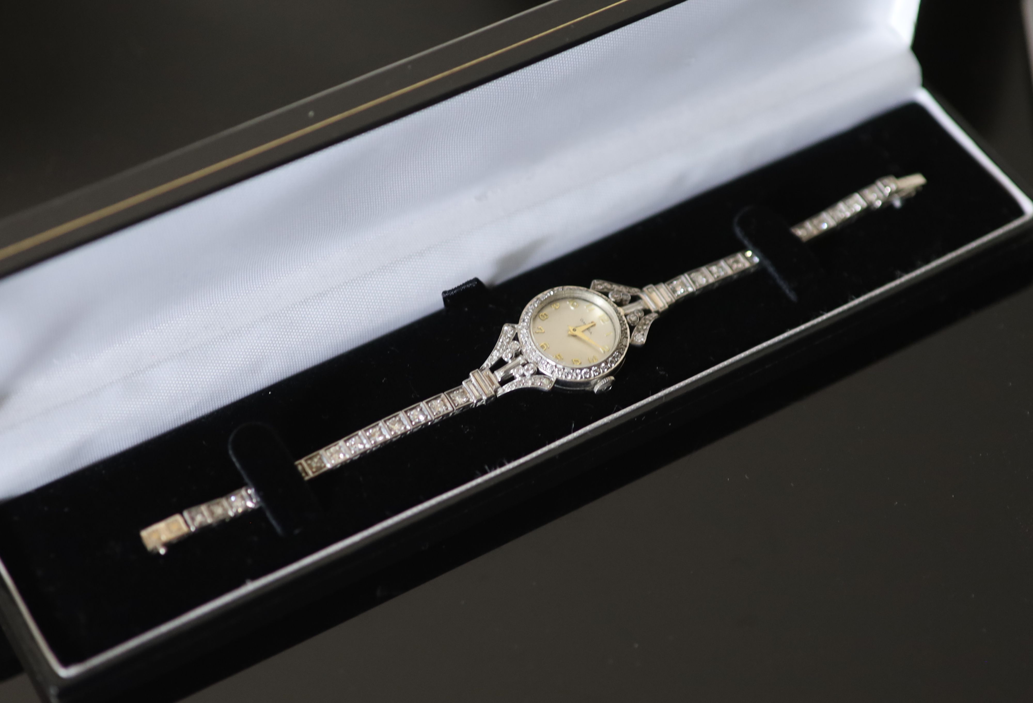A ladys early 1960s 18ct gold, palladium and diamond set Omega manual wind cocktail watch, on diamond set bracelet,